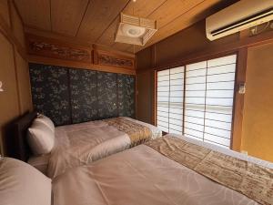 a bedroom with two beds and a window at P-Stay宮島中西町 in Hatsukaichi