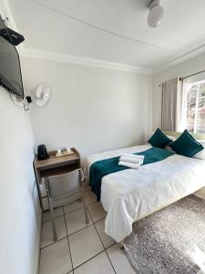 a bedroom with two beds and a table and a television at Creekside Guest House Middelburg in Middelburg