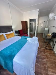 a large white bed in a room with a table at Creekside Guest House Middelburg in Middelburg