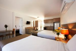 Habitación de hotel con 2 camas, mesa y cocina en Adelong Motel en Narrabri