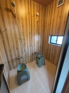 a bathroom with a toilet and a shower with wooden walls at P-Stay宮島中西町 in Hatsukaichi