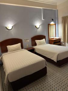 a hotel room with two beds and a window at New Caspian Hotel in Ipoh
