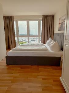Una cama grande en una habitación con una ventana grande. en Frisch renoviertes FH Südblick am Meer in Breege, Meerblick von allen drei Etagen, Terrasse, Balkon, Sauna und Parkplatz, en Breege