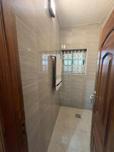 Un baño con ducha con puerta de cristal. en Kasoa Stay, en Kasoa 13 fotos más