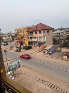 Un coche rojo circulando por una calle de la ciudad con edificios. en Kasoa Stay, en Kasoa