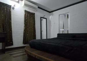 a bedroom with a bed and a window with curtains at Villa Ilham in Langkawi Intl