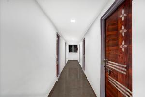 a corridor with white walls and a wooden door at Collection O Laxmi Chowk Hinjewadi in Hinjewadi