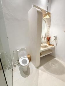 a white bathroom with a toilet and a mirror at Momy Breeze Uluwatu in Bingin Beach +26 photos