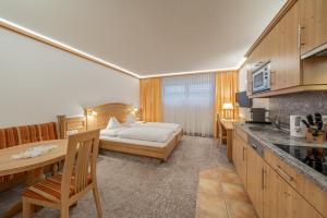 a hotel room with a bed and a table and a kitchen at Alpenresidenz am Mühlbach in Obergurgl