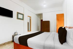 a bedroom with a white and black bed and a television at Collection O Candolim Beach Formerly Poornima Place in Candolim