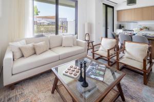 a living room with a couch and a table at Frank Porter - Parkside 2, Emaar South in Ghantoot