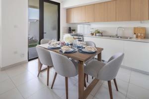a kitchen with a table and chairs in a kitchen at Frank Porter - Parkside 2, Emaar South in Ghantoot