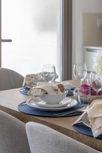 a table with a plate and wine glasses on it at Frank Porter - Parkside 2, Emaar South in Ghantoot +35 photos