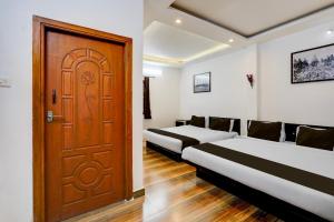 Cette chambre comprend 2 lits et une porte en bois. dans l'établissement Super Townhouse Auroville Beach Formerly De Heritage, à Kottakupam