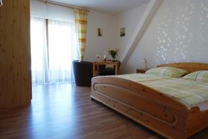a bedroom with a wooden bed and a large window at Weingut Pension Heinz Dostert in Nittel
