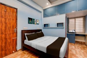 a bedroom with a bed with blue walls and a wooden door at Hotel O Ashok Nagar Metro Station Chennai Formerly G Cloud in Chennai