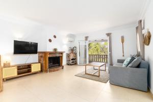 a living room with a tv and a couch and a fireplace at Villa Escaletas in Cala Santanyi