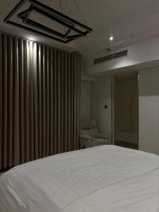 a bedroom with a white bed and a chair at Elegant apartment overlooking the sea in Jeddah