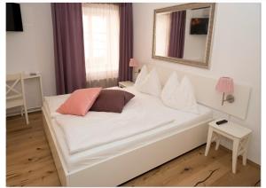 a white bed with pillows on it in a room at Madar Café Restaurant zum Fürsten in Melk