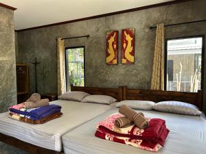 une chambre avec deux lits avec des serviettes dessus dans l'établissement บ้านสราญรัตน์, à Ban On Luai