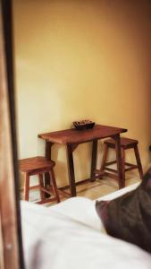 einen Holztisch in einem Zimmer mit zwei Hockern in der Unterkunft Boutique House Nipha in Chiang Mai