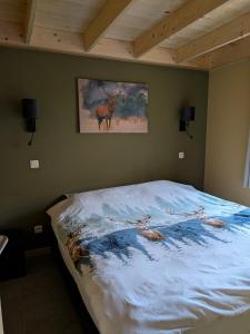 a bed with a painting of a deer on the wall at Châlet des Cerfs Durbuy in Somme-Leuze