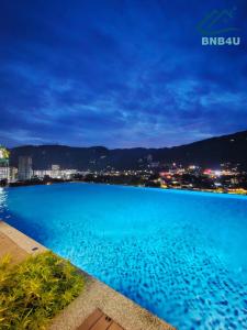 - une vue sur une piscine bleue la nuit dans l'établissement Minimalist Dual-Key Stay with 4BR at Farlim Penang, à Ayer Itam