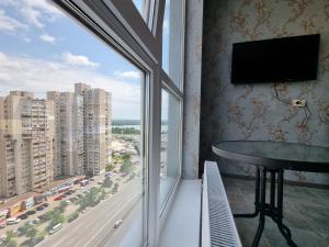 a room with a large window with a table and a tv at Your Flat Lebedinny in Kyiv +4 photos