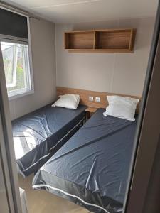 a small room with two beds and a window at amorosa mobil home in Canet-en-Roussillon