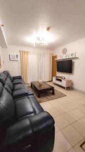 a living room with a black leather couch and a table at Comfy Condo Mactan Cebu in Sampong