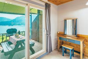 a room with a balcony with a table and a glass door at Sinbibada pension in Geoje 