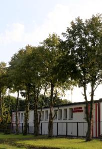 a white building with trees in front of it at COMBO noclegi pracownicze, dla firm 