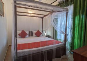 ein Schlafzimmer mit einem Himmelbett und roten Kissen in der Unterkunft Serenità Moon Villa in Tangalle