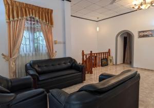 ein Wohnzimmer mit 2 Ledersofas und einem Fenster in der Unterkunft Serenità Moon Villa in Tangalle