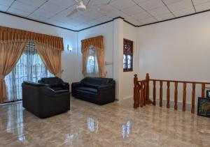 ein Wohnzimmer mit 2 Ledersesseln und Fenstern in der Unterkunft Serenità Moon Villa in Tangalle