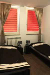 a bedroom with two beds and two windows with red blinds at COMBO noclegi pracownicze, dla firm 