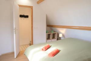 a bedroom with a bed with two pink pillows on it at La Sellerie et Le Relais des Hortensias in Graincourt