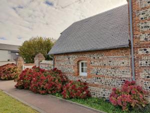 une maison en briques avec des fleurs rouges devant elle dans l'établissement Le Relais des Hortensias, à La Celle-sous-Gouzon