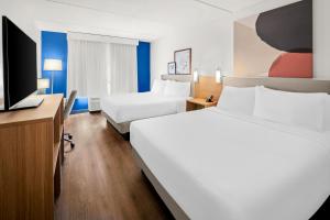 a hotel room with two beds and a flat screen tv at Spark by Hilton in Woodbridge