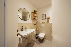 a bathroom with a sink and a toilet and a mirror at HYGGE HOMES - Apartment 'Urban Nest' - Schlossnähe trifft Design in Celle +68 photos
