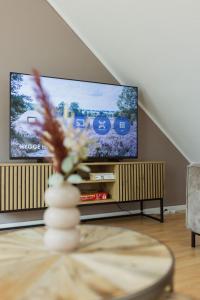a living room with a flat screen tv and a table at HYGGE HOMES - Apartment 'Urban Nest' - Schlossnähe trifft Design in Celle