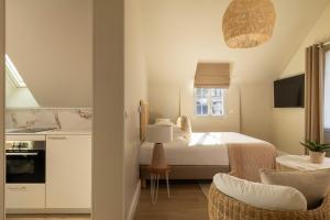 a bedroom with a white bed and a kitchen at Villa Léa, l'écrin du Fer à Cheval in Trouville-sur-Mer