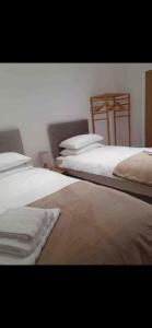 una camera con tre letti con lenzuola bianche di The chalet a Childwall