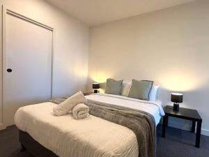 a bedroom with two beds and a table with lamps at Full of Fun shopping 1BR stay at Clayton in Clayton North +2 photos