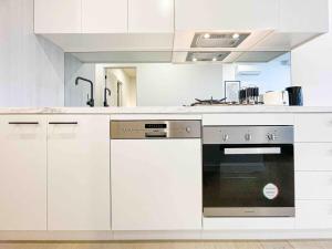 a kitchen with white cabinets and an oven at Full of Fun shopping 1BR stay at Clayton in Clayton North