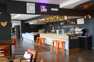 a restaurant with a bar with orange stools at ibis Beauvais Aéroport in Beauvais