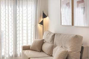 - un canapé blanc dans le salon doté d'une fenêtre dans l'établissement Dobo Málaga Perchel, à Malaga