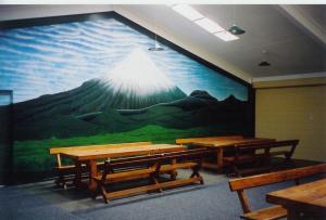 a room with tables and a large painting on the wall at Egmont Eco Leisure Park & Backpackers in New Plymouth