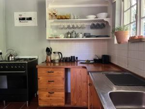 The Little Thatch Cottage في غرايتون: مطبخ بدولاب خشبي وموقد ومغسلة