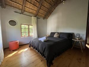 The Little Thatch Cottage في غرايتون: غرفة نوم مع سرير مع لحاف أسود